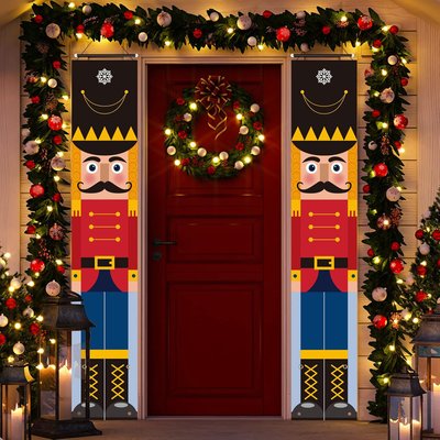 2 casse-noisettes géants rouge et bleu de chaque côté d'une porte d'entrée rouge décoré par une guirlande de Noel