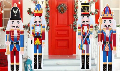 4 Figurines Casse-noisettes grandeur nature à l'entrée d'une maison avec la porte rouge décorée d'une guirlande de Noël 