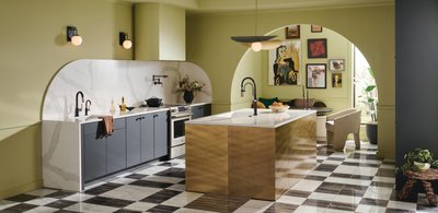 Cuisine moderne et artistique avec robinetterie noire mate de la collection Litze par Brizo, îlot central doré et mur d’accent vert pâle.