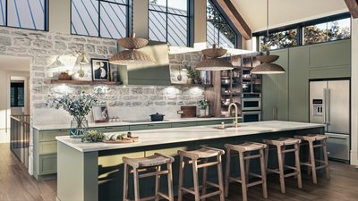 Cuisine d'une beauté à couper le souffle dans la Maison Tanguay 2025, avec des armoires vert sauge, un îlot spacieux avec des tabourets en bois, un mur de pierres apparentes, et des luminaires en osier suspendus.