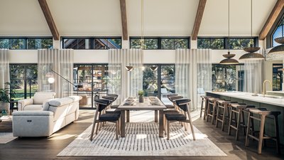 Salle à manger lumineuse de la Maison Maurice-Tanguay 2025, avec une table en bois, huit chaises élégantes, un tapis à motifs subtils, et une grande fenestration laissant entrer la lumière naturelle.