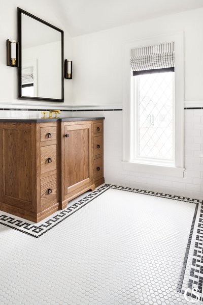 Salle de bain classique avec un meuble-lavabo en bois naturel, comptoir noir, robinetterie dorée