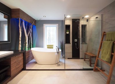 Salle de bain contemporaine avec baignoire autoportante blanche, robinet sur pied chromé, décor mural avec troncs de bouleaux et éclairage coloré, douche vitrée spacieuse avec mur d'accent noir, banc en bois, meuble-lavabo en bois foncé avec comptoir noir et porte-serviettes en bois avec serviettes vertes.