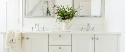 Salle de bain lumineuse avec meuble-lavabo blanc, robinetterie argentée, miroir décoratif