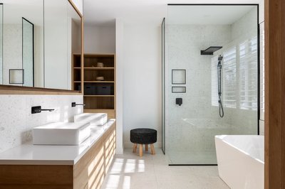 Salle de bain moderne avec meuble-lavabo double en bois naturel, vasques blanches rectangulaires, robinetterie noire murale, grand miroir encadré en bois