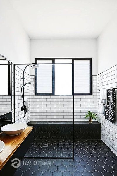 Salle de bain contemporaine avec douche italienne, carrelage mural blanc type métro, sol en tuiles noires hexagonales, et fenêtre à cadre noir.