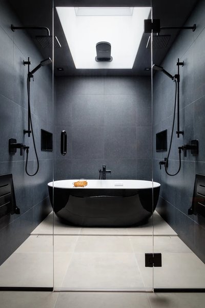 Magnifique salle de bain noire au style moderne et luxueux avec une baignoire autoportante noire au fini brillant, contrastant avec son intérieur blanc.