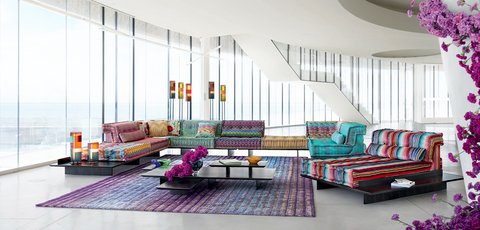 Canapé modulable Mah Jong de Roche Bobois avec tissus Missoni colorés, disposé sur des plateformes noires, dans un intérieur moderne et lumineux avec vue sur l'extérieur.