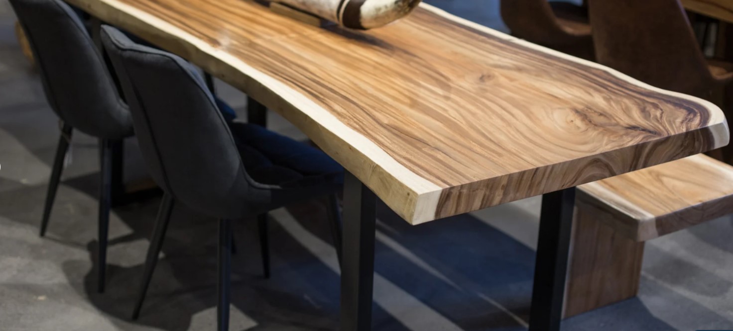 Table en bois massif avec bordure naturelle, pieds en métal noir et chaises en velours noir, dans un intérieur moderne