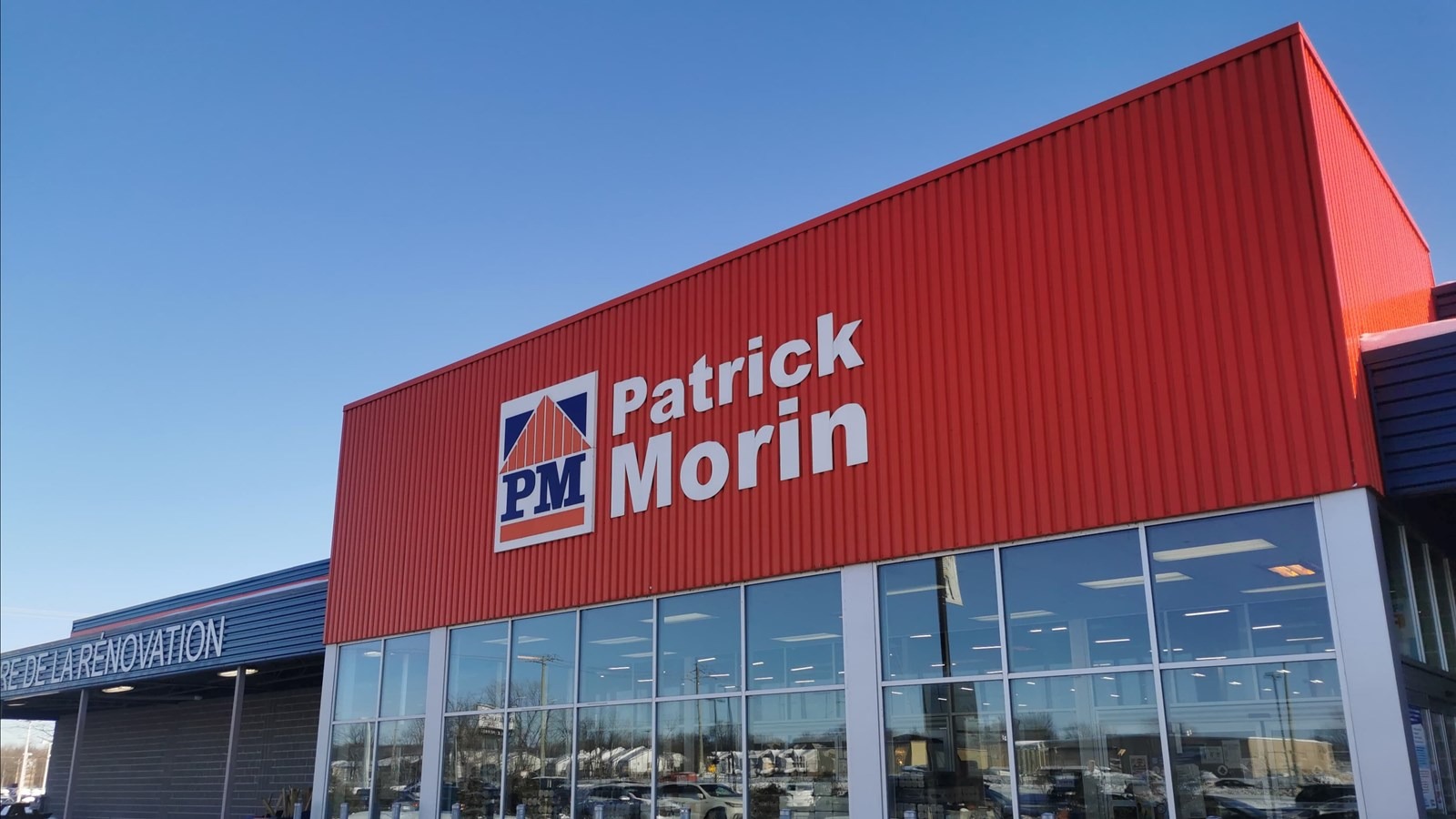 Façade d’un magasin Patrick Morin avec logo sur un mur rouge, spécialisé dans la rénovation et les matériaux de construction au Québec.